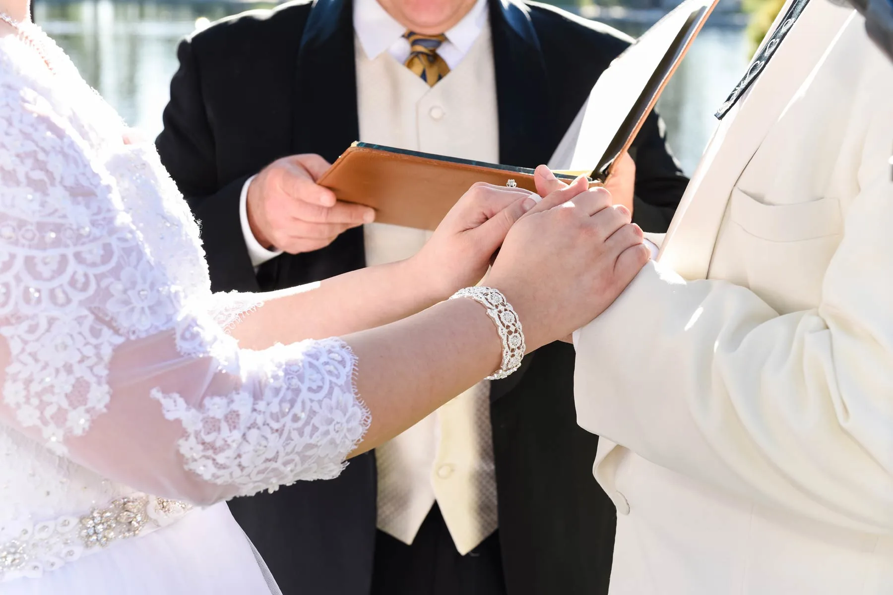fash close up of wedding officiant in suit and tie reading from folder and watching couple holding hands as they exchange vows